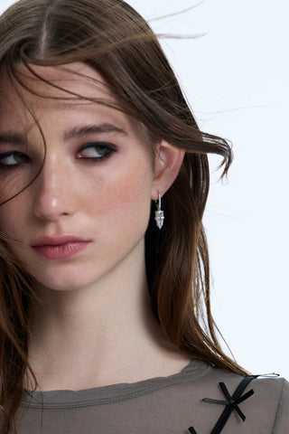 A MODEL LOOKING OFF TO THE SIDE WITH HER HAIR BLOWING IN FRONT OF HER FACE, WEARING THE SUPERNOVA DROP LEVERBACK EARRINGS