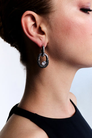 CLOSE UP OF THE SIDE PROFILE OF A MODEL AS SHE WEARS A HIGH-NECK BLACK TOP AND THE TURN UP THE VOLUME DOORKNOCKER EARRINGS