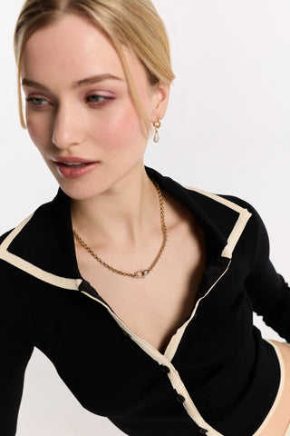 A MODEL IN A BLACK TOP WITH AN OPEN NECKLINE, WEARING THE GEMINI PAVE CLASP COLLAR NECKALCE AND PAVE DROP HUGGIE EARRINGS