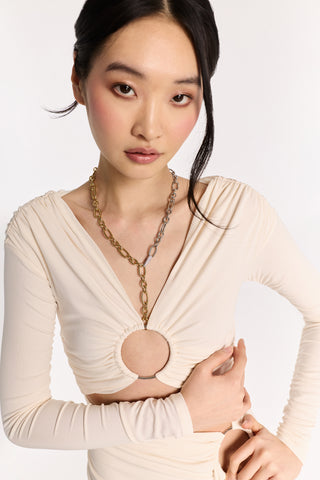 A MODEL LOOKING AT THE CAMERA WITH HER HAND ACROSS HER BODY ON HER OPPOSITE HIP, WHILE WEARING A WHITE OUTFIT AND THE GEMINI LARGE LINK NECKLACE