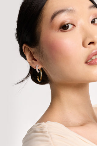 CLOSE UP OF HALF OF A MODEL’S FACE WITH HER HAIR TUCKED BEHIND HER EAR WHILE WEARING THE GEMINI FRONT BACK EARRINGS