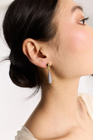 CLOSE UP OF THE SIDE PROFILE OF A MODEL, WITH HER HAIR TUCKED BEHIND HER EAR WHILE WEARING THE GEMINI PAVE BOTTOM DROP EARRINGS