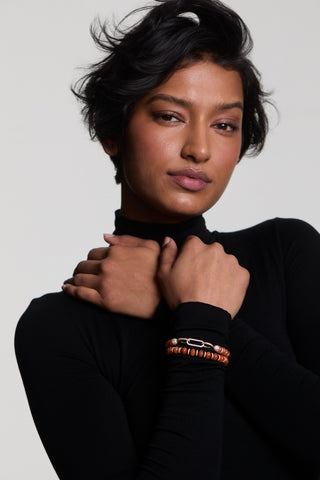 A MODEL WEARING A BLACK TURTLENECK WITH HER ARMS CROSSED UP TO HER CHEST, WEARING THE BOUJEE BEADS CARNELIAN BRACELET