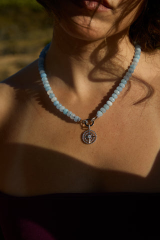 CLOSE UP OF A MODEL’S CHEST WEARING THE BEADS OF PARADISE NAUT PENDANT NECKLACE, AS THE SUN SHINES ON IT