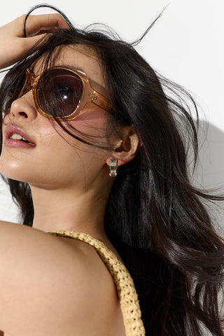 MODEL WITH BIG SUNGLASSES AND HAIR FLOWING BEHIND HER, WEARING THE MOJITO BLUE J HOOP EARRINGS