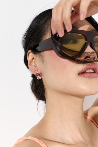 CLOSE UP OF A MODEL WEARING SUNGLASSES AND THE MOJITO PINK J HOOP EARRINGS, WITH HER HAND UP TO HER GLASSES AND BLOWING HAIR 