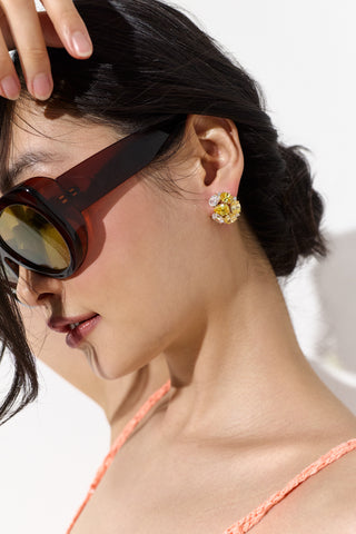 SIDE PROFILE OF A MODEL WEARING SUNGLASSES AND THE MOJITO BUTTON STUD EARRINGS, WITH HER HAND UP TO HER HEAD