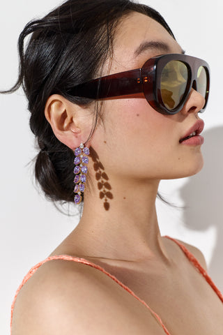 CLOSE UP OF THE SIDE PROFILE OF A MODEL, WEARING SUNGLASSES AND THE MOJITO PURPLE DOUBLE LINEAR EARRINGS