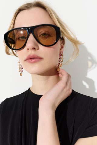CLOSE UP OF MODEL LOOKING AT THE CAMERA WITH HER HAND UP TO HER NECK, WEARING SUNGLASSES AND THE MOJITO PINK DOUBLE LINEAR EARRINGS 