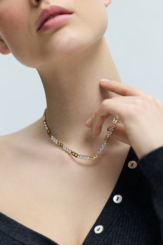CLOSE UP OF A MODEL’S CHEST WEARING A GRAY SWEATER AND THE DELANCEY ALL AROUND COLLAR NECKLACE, AS SHE LIFTS A SECTION OF THE CHAIN LINKS WITH HER HAND.