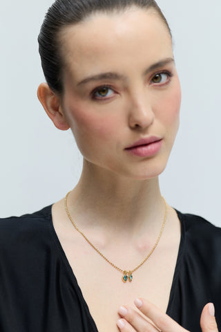 A MODEL LOOKING AT THE CAMERA WEARING A BLACK TOP AND THE DELANCEY AQUA CHARM PENDANT NECKLACE