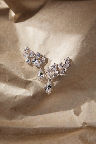 RIVIERA CLUSTER DROP EARRINGS IN RHODIUM PLATING AGAINST A BROWN PAPER BACKDROP