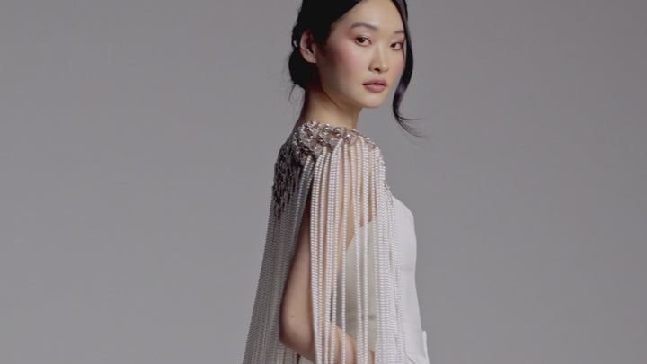 Model wearing a white suit with Nadri's Pearl and CZ cape. She is elegantly moving and showing off the cape from every angle.