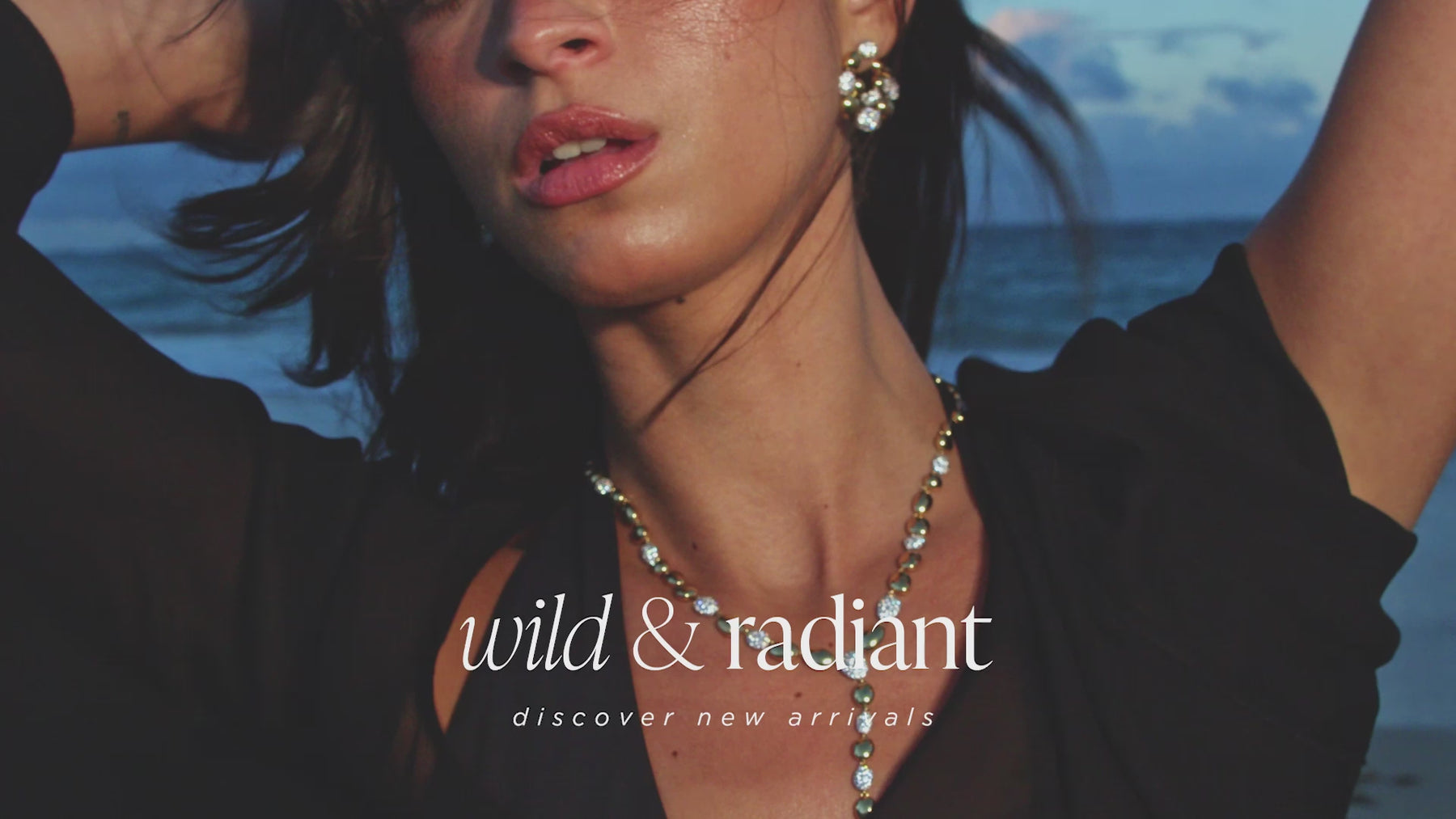 Wild and Radiant. Discover New Arrivals. Video shows a model with dark hair in a black dress running on a beach wearing two tone pave cz jewelry from Nadri's Pebbles collection.