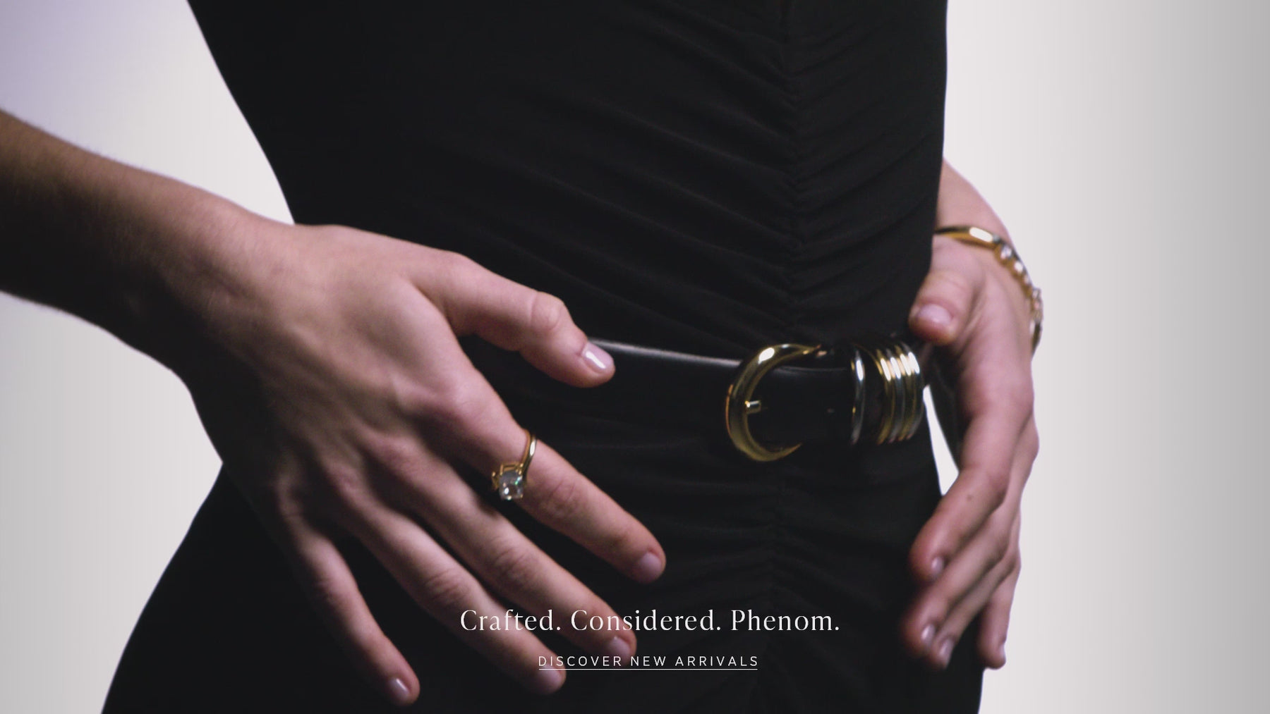 Video of a model wearing a sleek black one-piece jumpsuit and Nadri's Phenom jewelry collection.  She is moving slowly  and the camera is focused on the jewelry which features emerald cut cubic zirconia stones and polished metal details. The text reads "Crafted. Considered. Phenom" and there is a button that says "Discover New Arrivals".