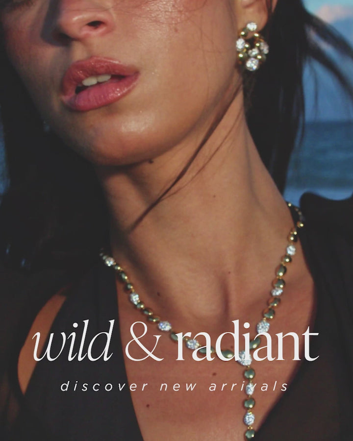 Wild and Radiant. Discover New Arrivals. Video shows a model with dark hair in a black dress running on a beach wearing two tone pave cz jewelry from Nadri's Pebbles collection.