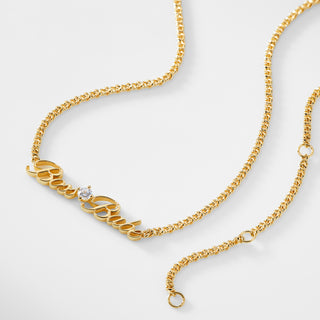 A gold chain necklace that says "Boss Babe" with a single cubic zirconia stone